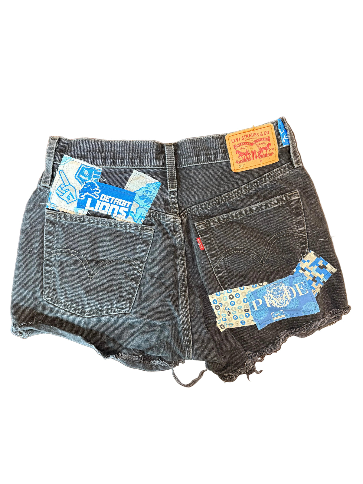 A pair of dark gray washed denim shorts laid flat on a brown wooden table, with several blue and white Levi's brand tags attached to the back pockets.