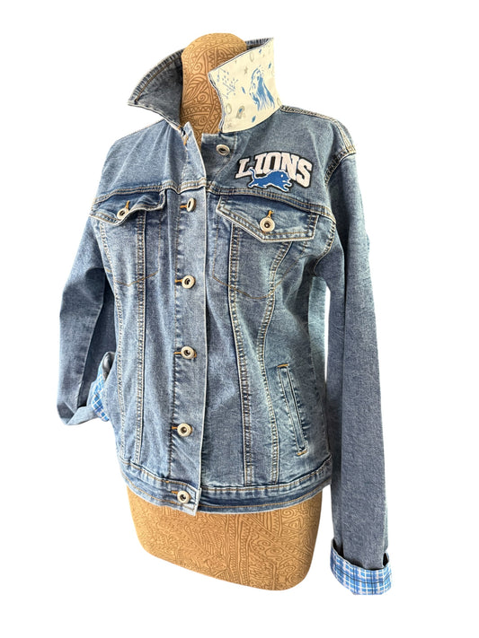 A light blue denim jacket with a 'LIONS' graphic on the chest, displayed on a tan dress form mannequin against a white background.
