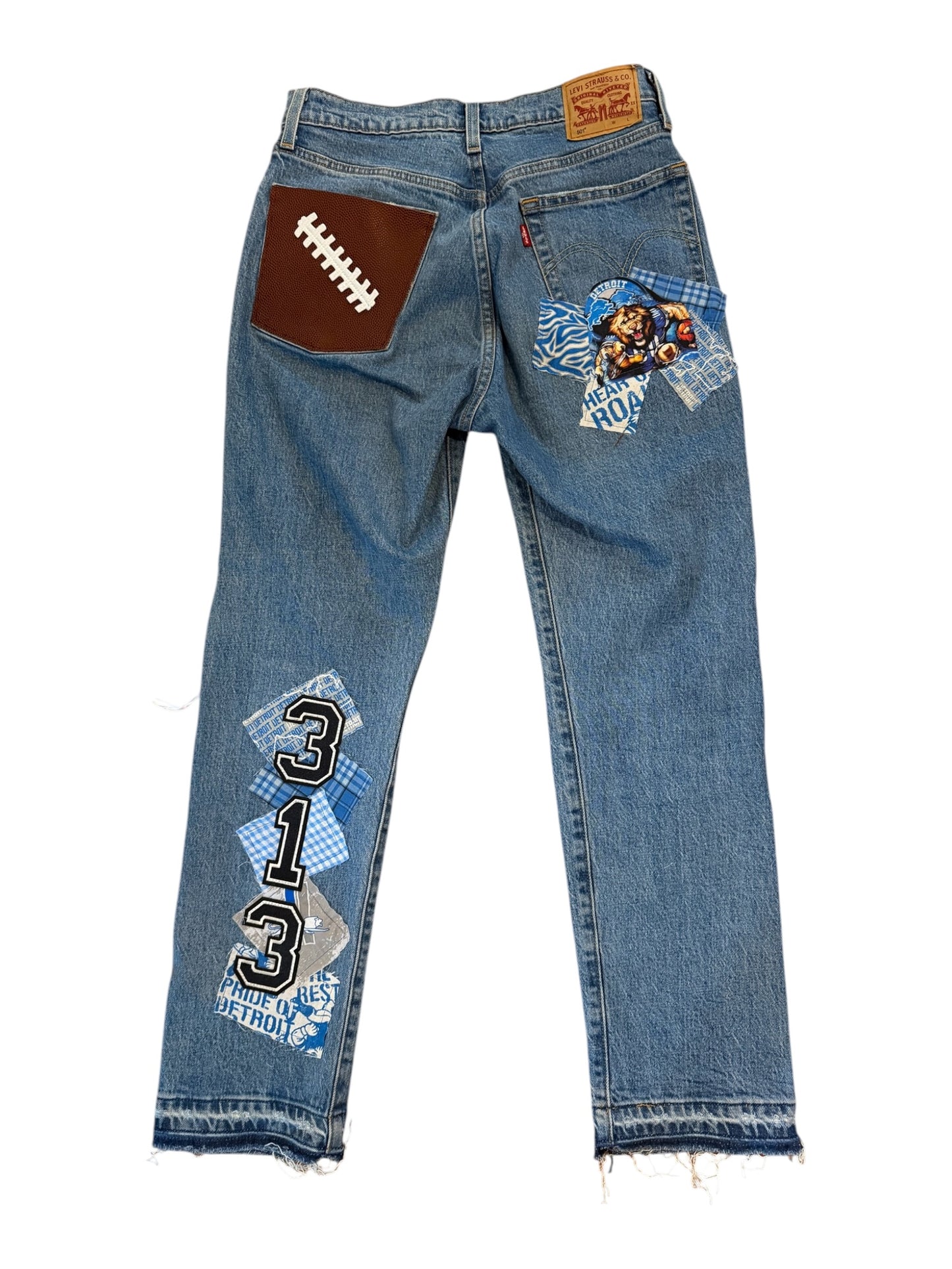 Light blue denim jeans with unique back pocket and thigh patch designs, featuring a brown football patch on the right back pocket and a blue graphic patch on the left back pocket. The left thigh features a blue and white patch with the number '313'.