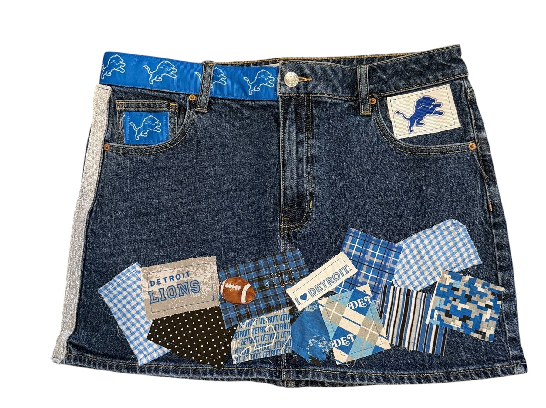 A denim patchwork mini skirt featuring blue and navy denim panels, gingham patterns, and various fabric patches, shown flat on a white background.
