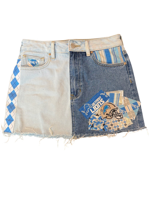 A split-design denim mini skirt made from two different washes of jeans, featuring Detroit Lions themed patches and a blue-and-white argyle pattern on a white background.