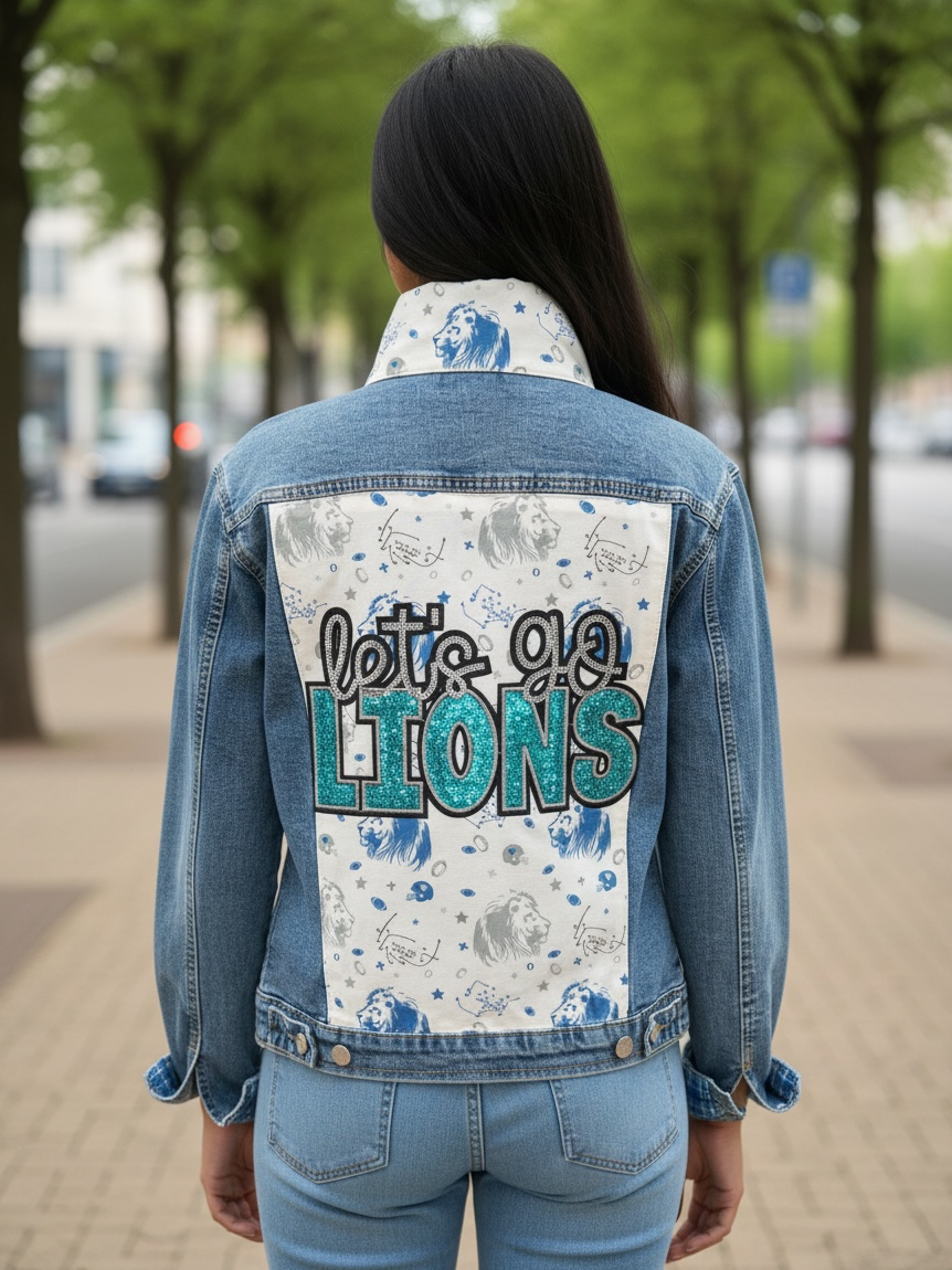 A person viewed from behind wearing a light blue denim jacket with a large back patch that reads "let's go. LIONS" in black and teal lettering over a white patterned background.