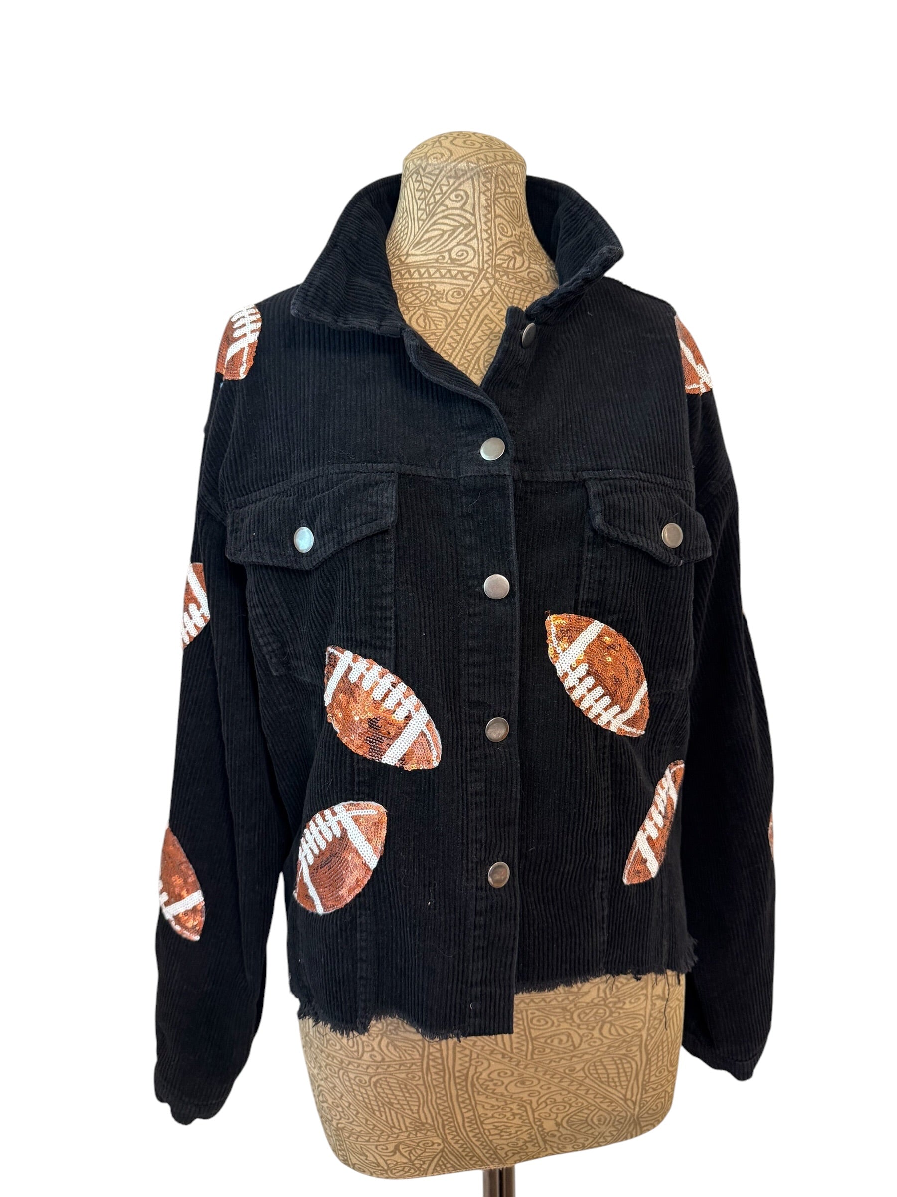 A black corduroy jacket with football patchwork details, displayed on a beige mannequin torso against a white background.