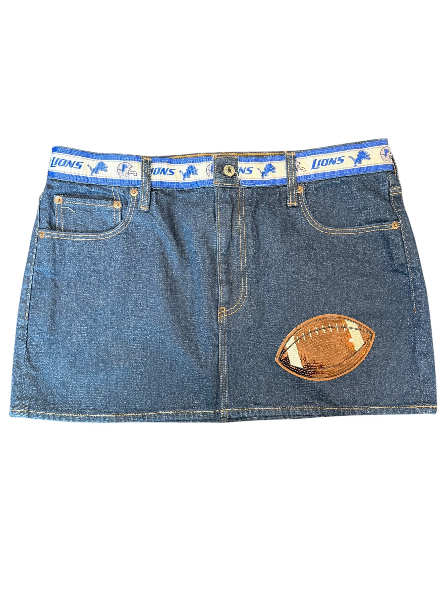 A blue denim mini skirt featuring a football patch on the left leg and a blue elastic waistband with 'Lions' text and animal logos.