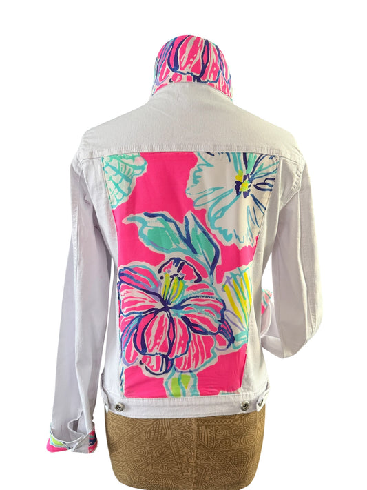 A white denim jacket shown from the back on a dress form, featuring a large vibrant pink tropical floral print panel on the back and a matching pink floral print hood, displayed against a white background.