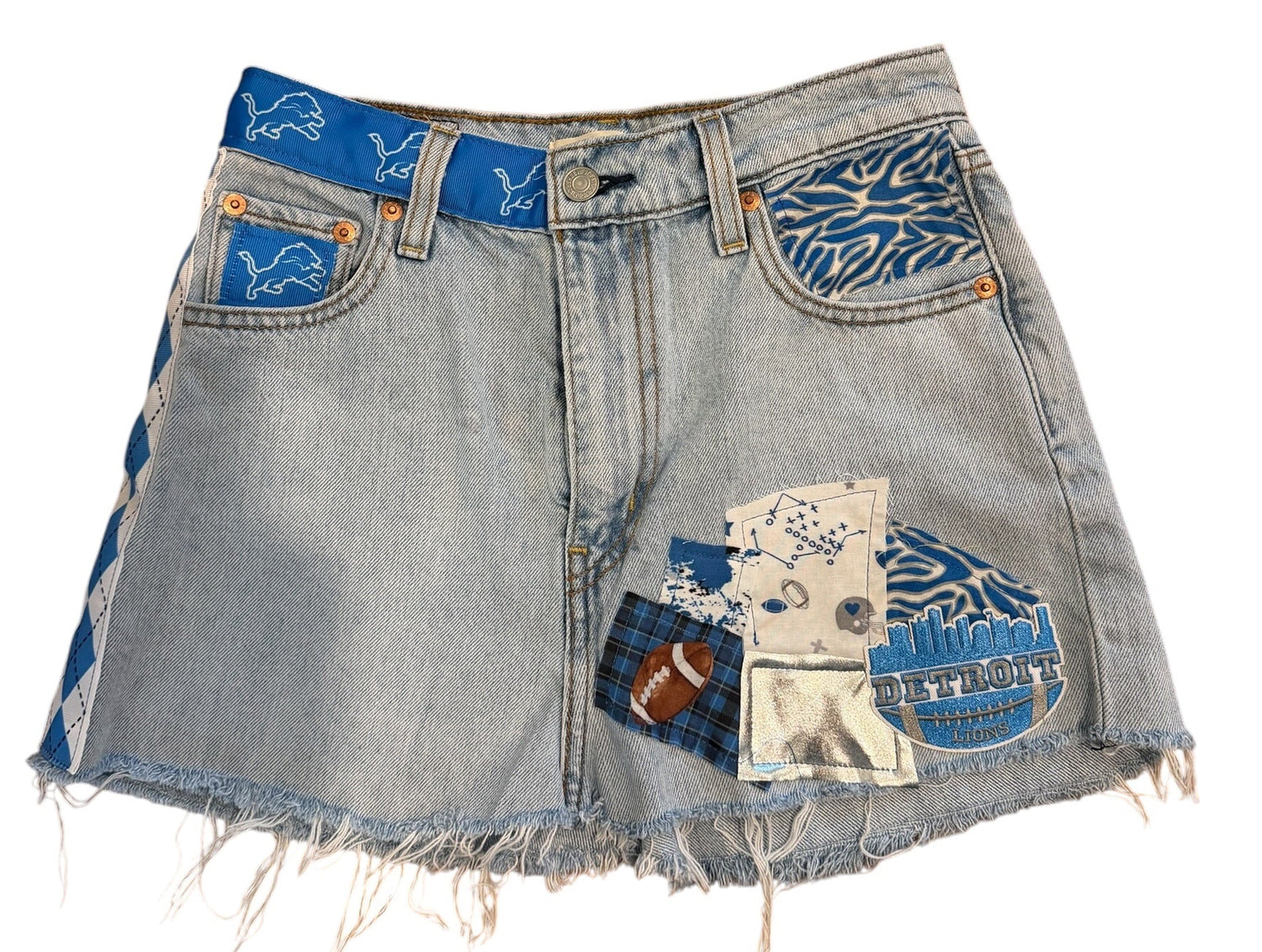 Light-wash denim shorts with frayed hems and decorative blue patchwork details on the back pockets, shown on a plain white background.