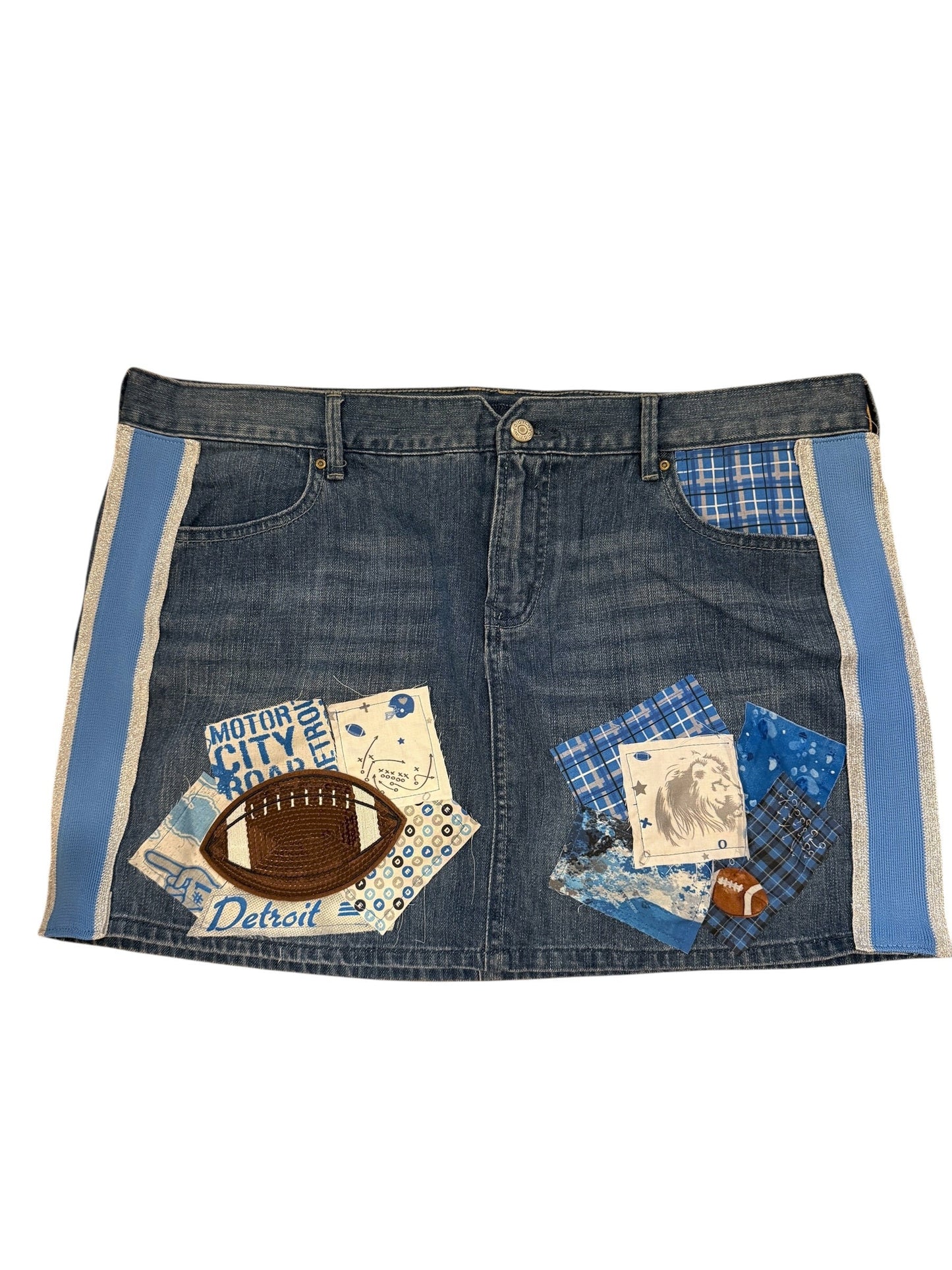 A denim apron or bib-style garment laid flat on a white background, featuring blue plaid and patchwork fabric accents, a football patch, and football-themed printed details.