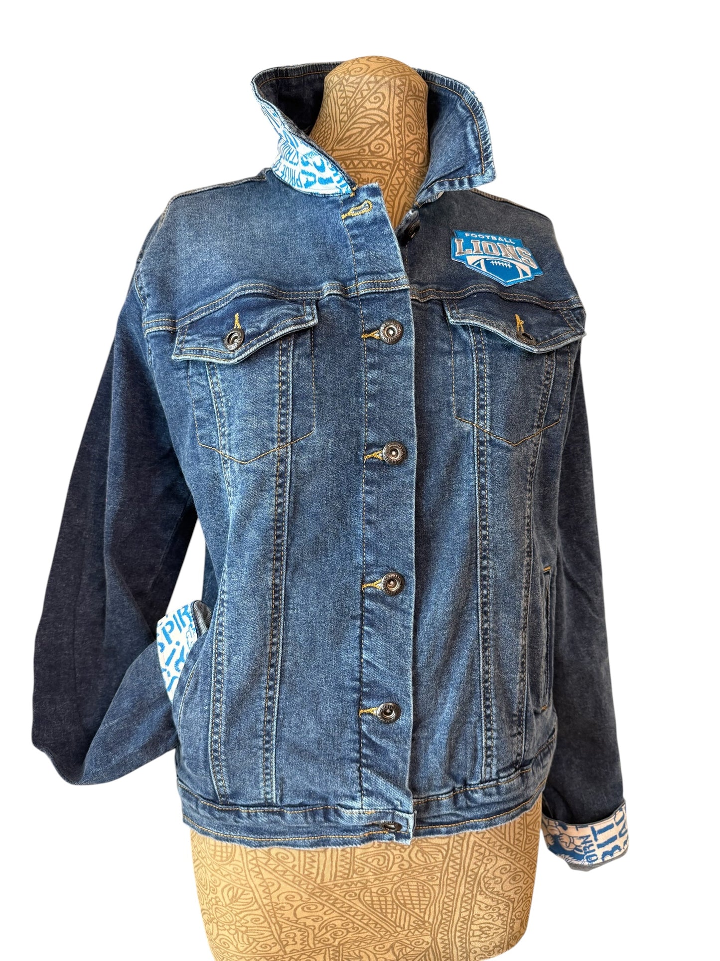 A women's denim jacket with contrasting dark navy sleeves and a light blue patterned lining on the collar, cuffs, and pockets, displayed on a tan mannequin torso against a white background.