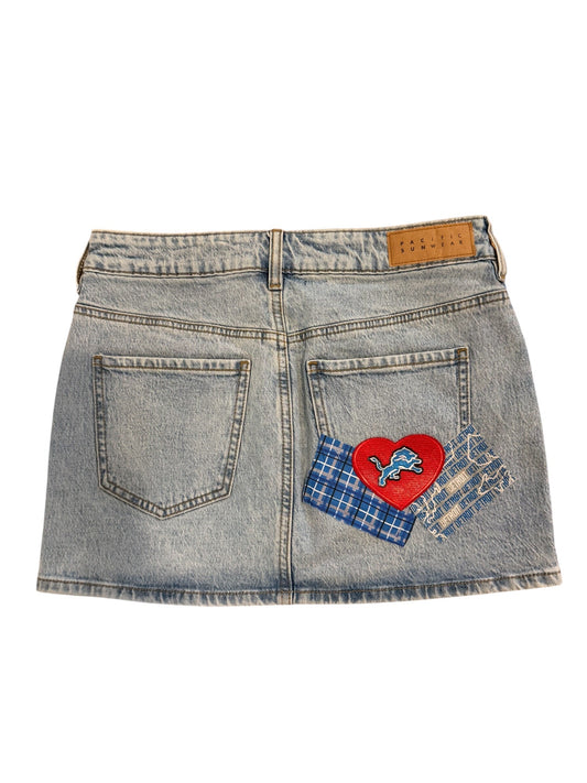 Light-wash denim shorts with a red heart patch, blue plaid fabric, and a small blue butterfly applique on the back pockets, shown flat on a white background.