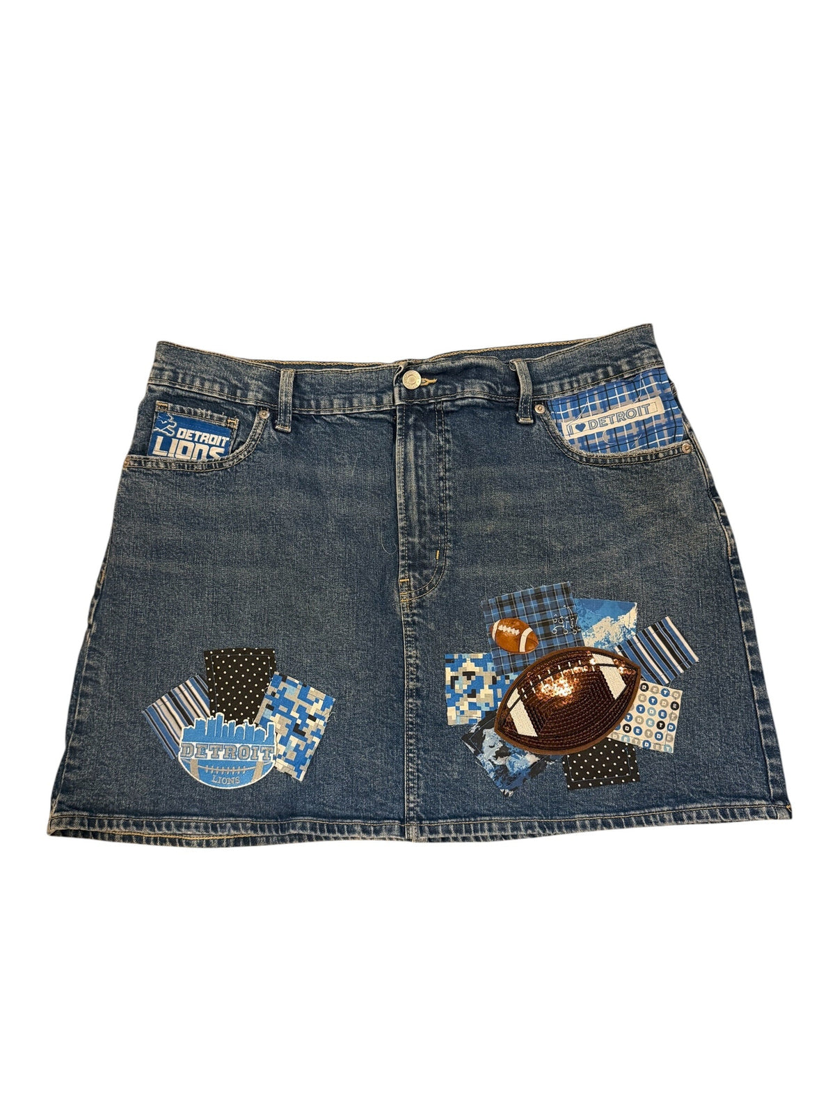 A pair of blue denim shorts featuring a patchwork design with various fabric prints, including plaid, polka dots, and a football motif, laid flat against a white background.