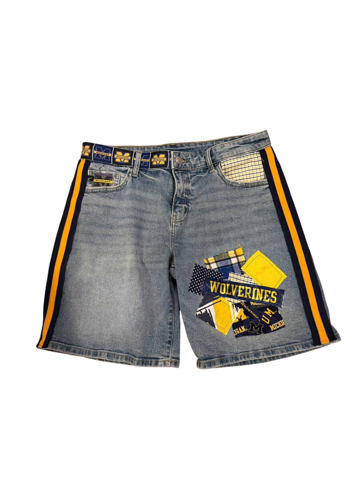 Light blue denim shorts featuring a Michigan Wolverines theme, with yellow and navy blue side stripes, a patterned back pocket, and a graphic patch on the left leg.