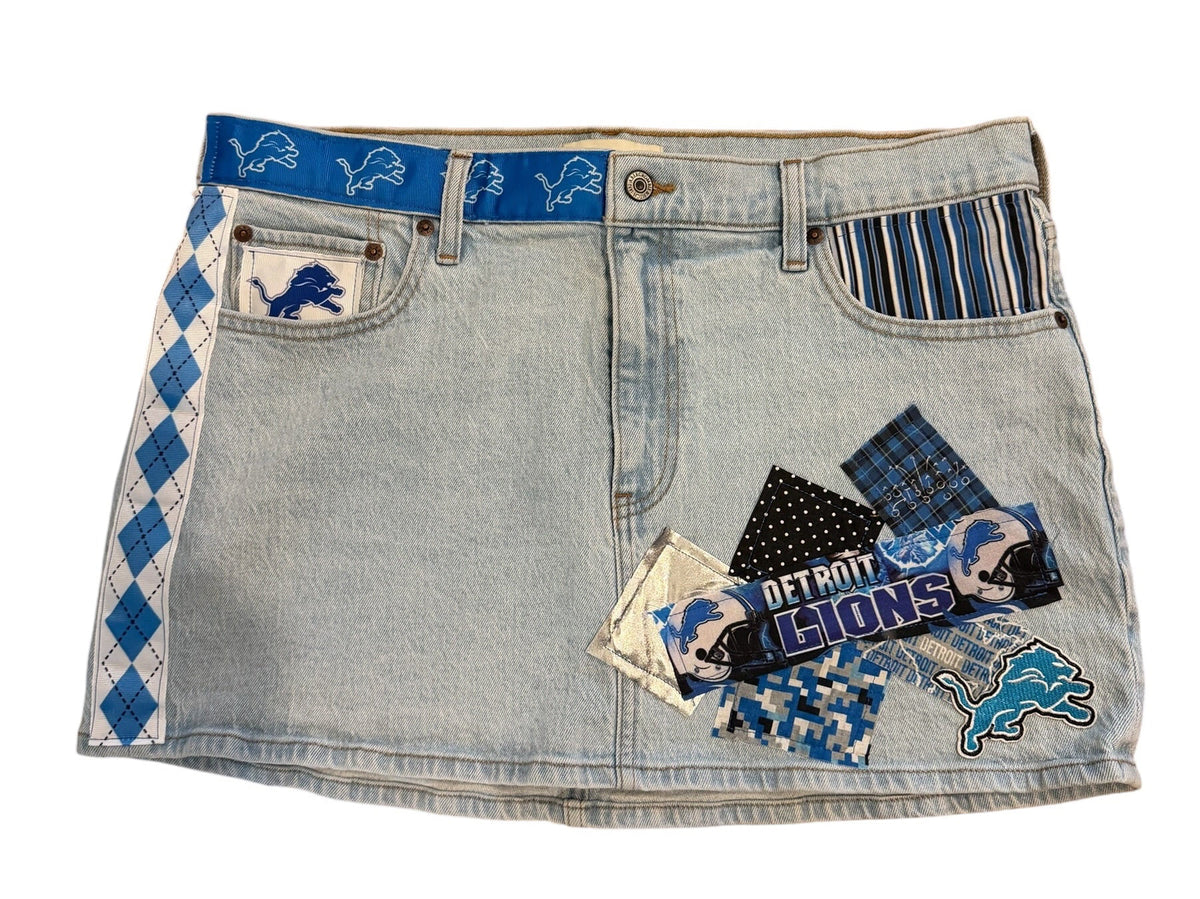 A light-wash denim mini skirt featuring blue and white argyle patterns on the waistband, a blue embroidered polo player on the pocket, and a patchwork collage of denim fabrics with 'Polo' and 'HUNTS' text on the front.