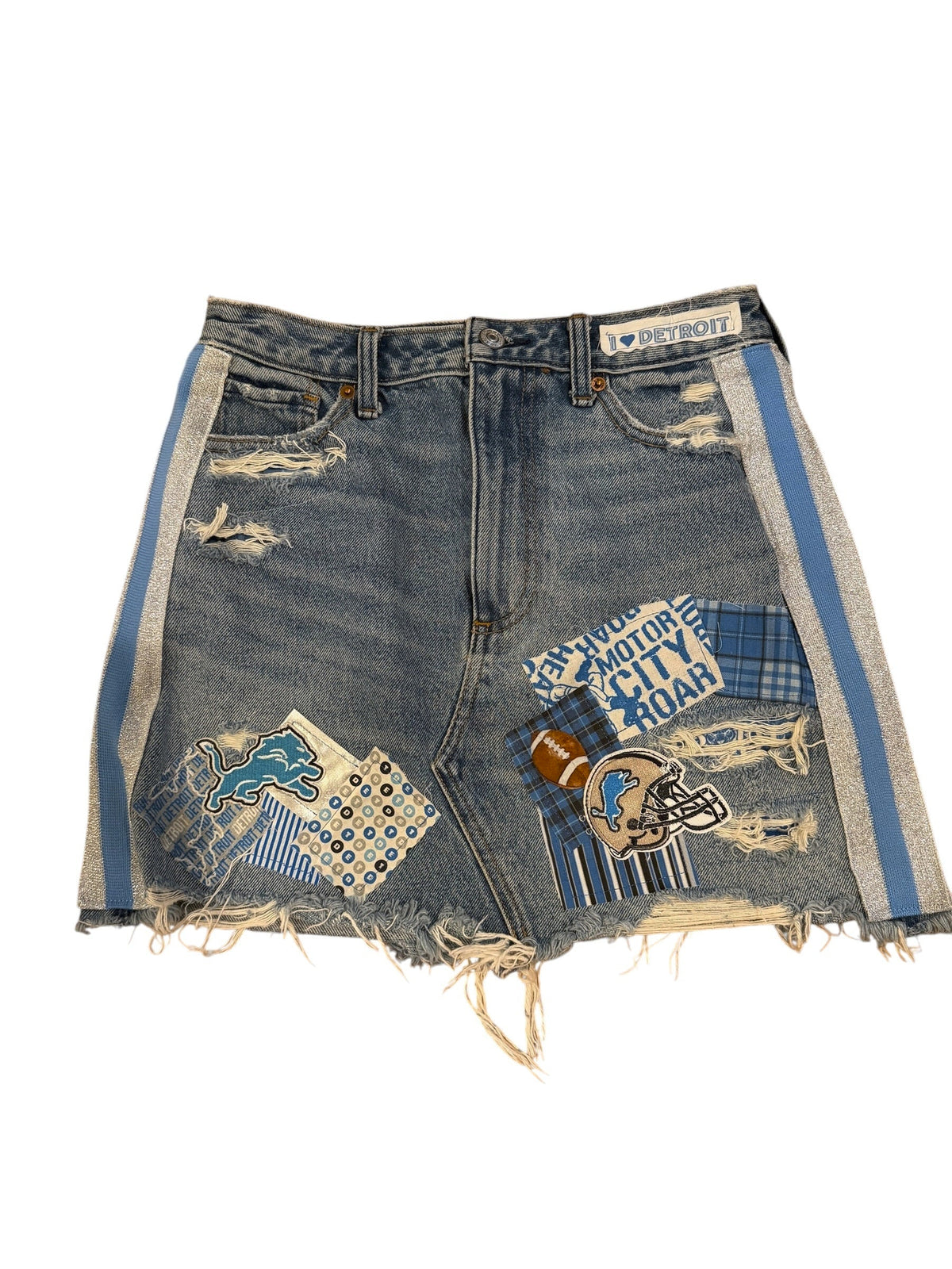Distressed denim shorts with frayed edges, featuring blue and white plaid patches, a football patch, and a blue and white striped trim, shown on a white background.