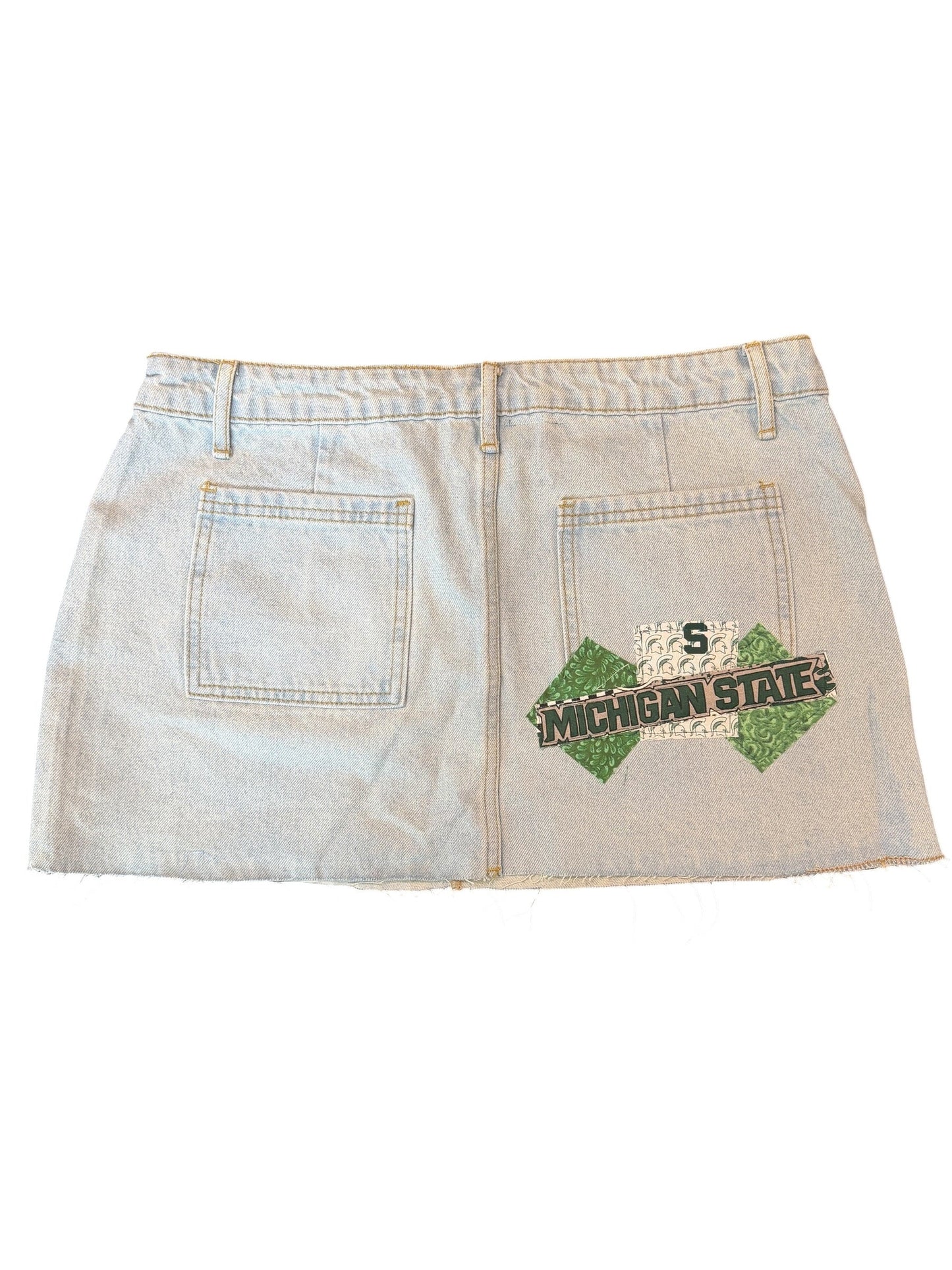 A light-wash denim skirt with a distressed design, featuring a green and black 'Jalen Smith' patch on the front pocket and a distressed '5' patch on the back pocket.