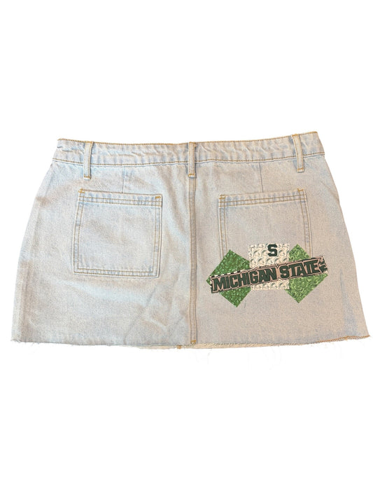 A light-wash denim skirt with a distressed design, featuring a green and black 'Jalen Smith' patch on the front pocket and a distressed '5' patch on the back pocket.