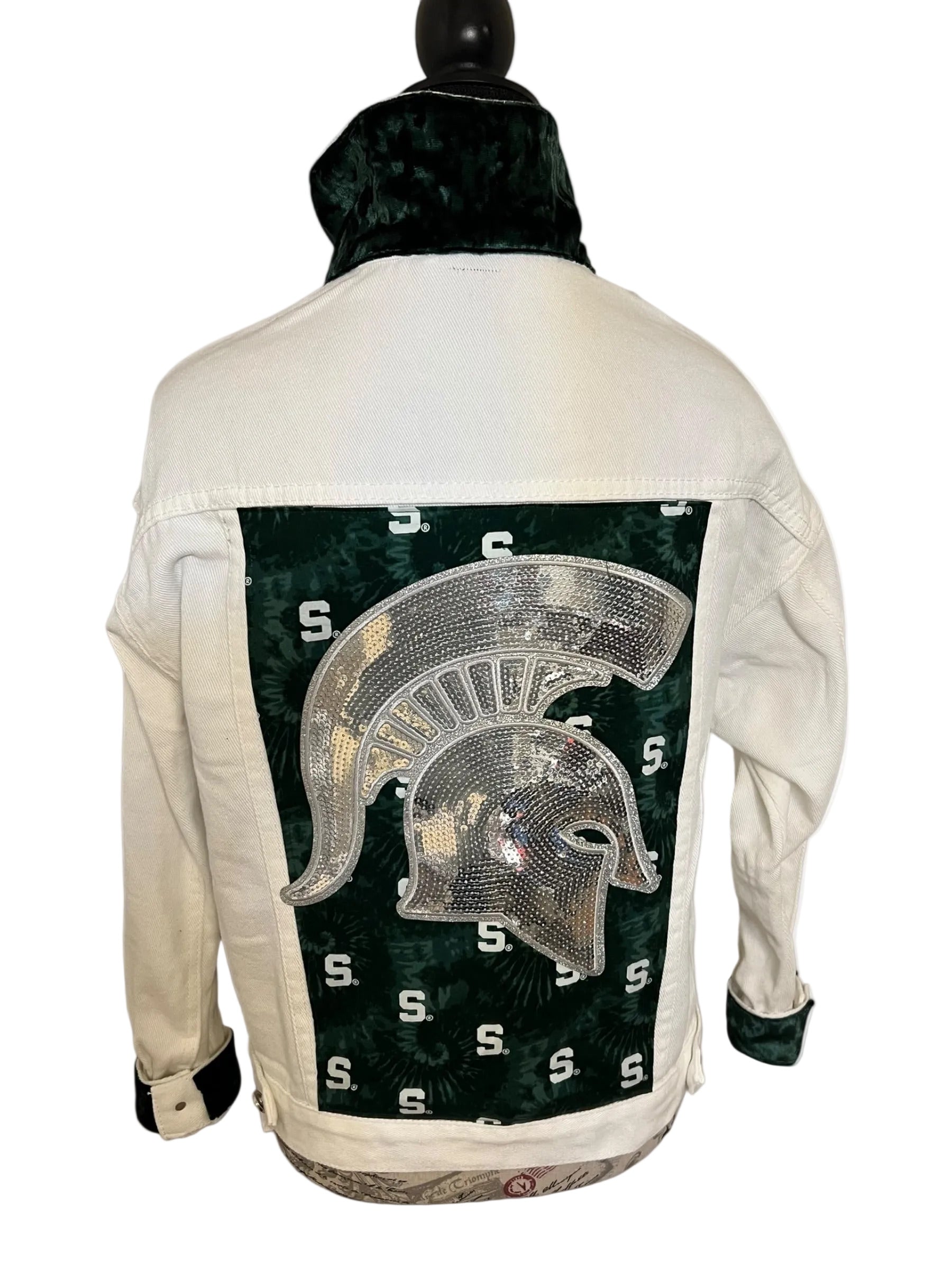 White denim jacket with a green and gold Spartan helmet design on the back